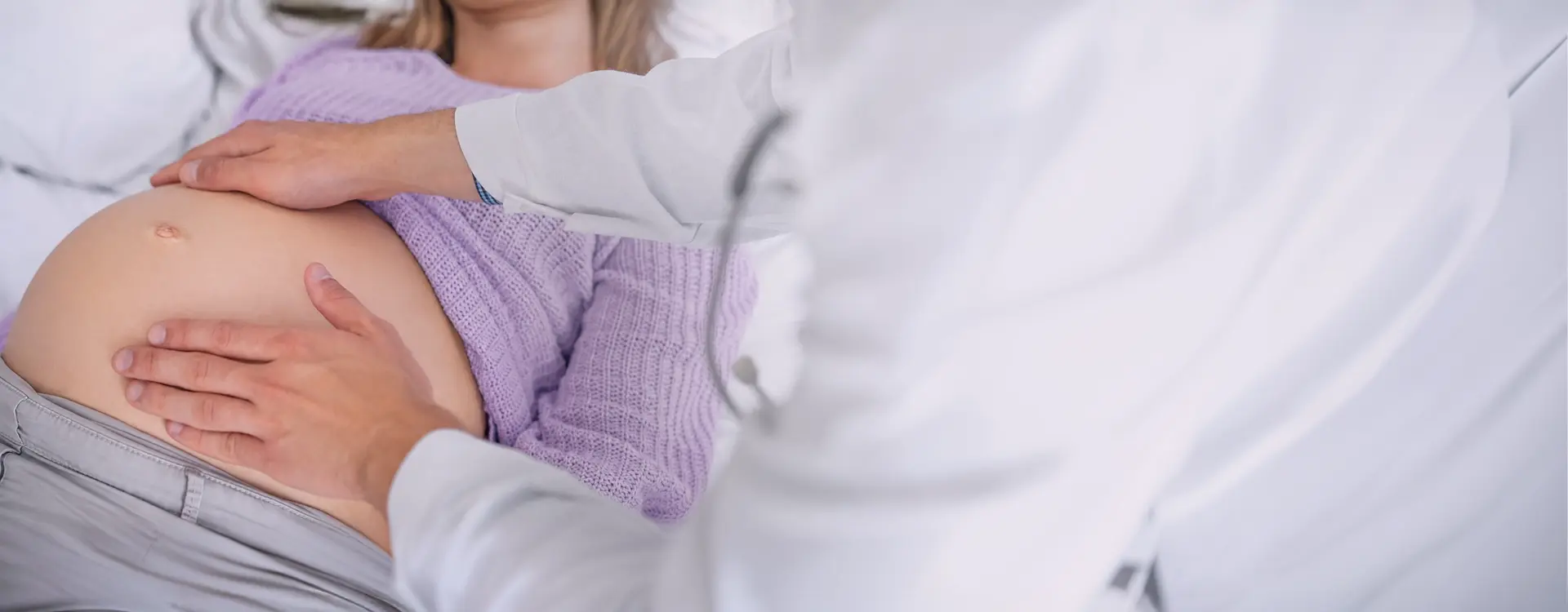Doctor performing an abdominal palpation examination on a pregnant woman lying down